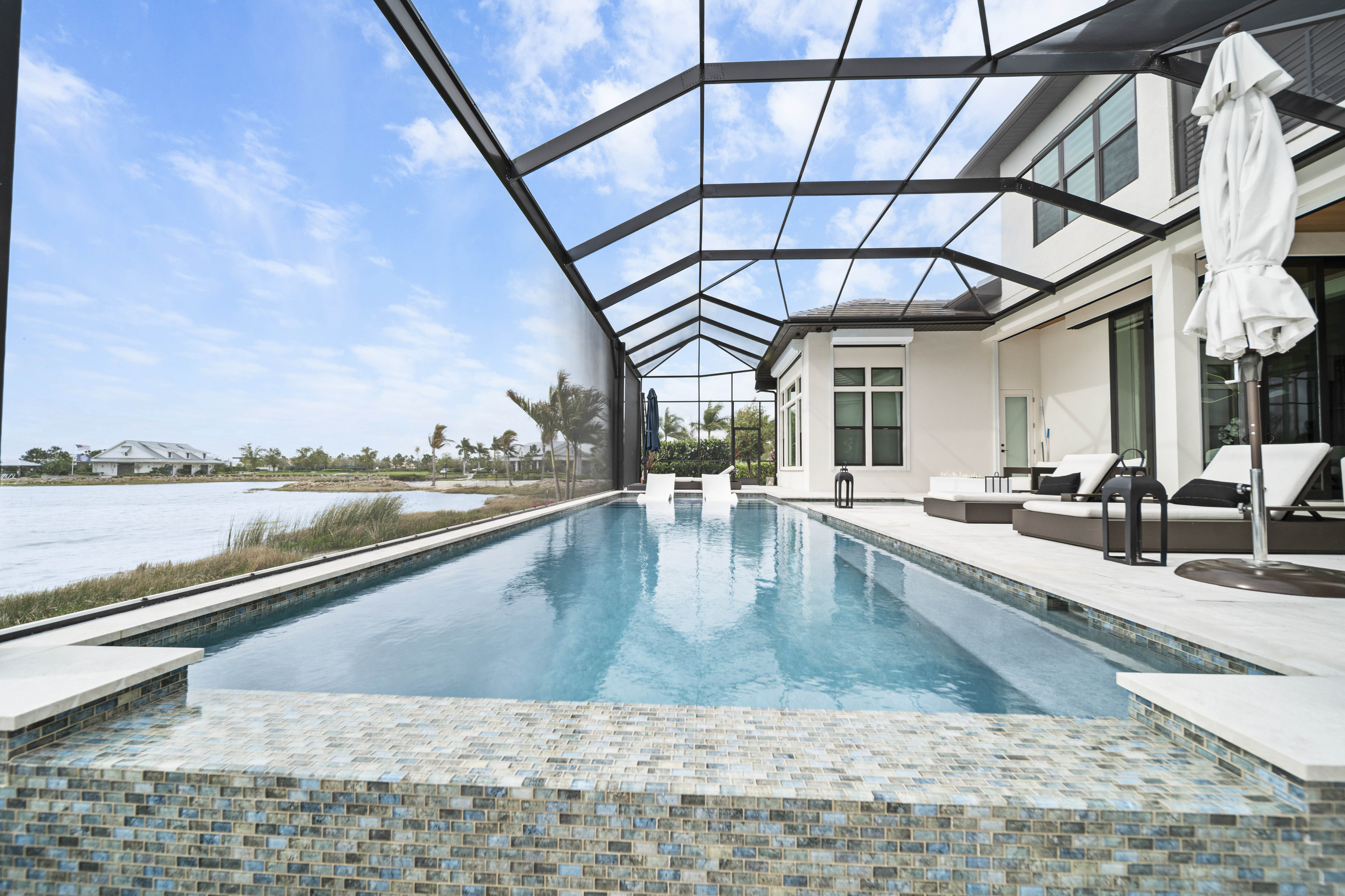 Resort-style pool with swim-up bar, lit fire feature, and outdoor seating at dusk - Swim Inc. custom pool Sarasota