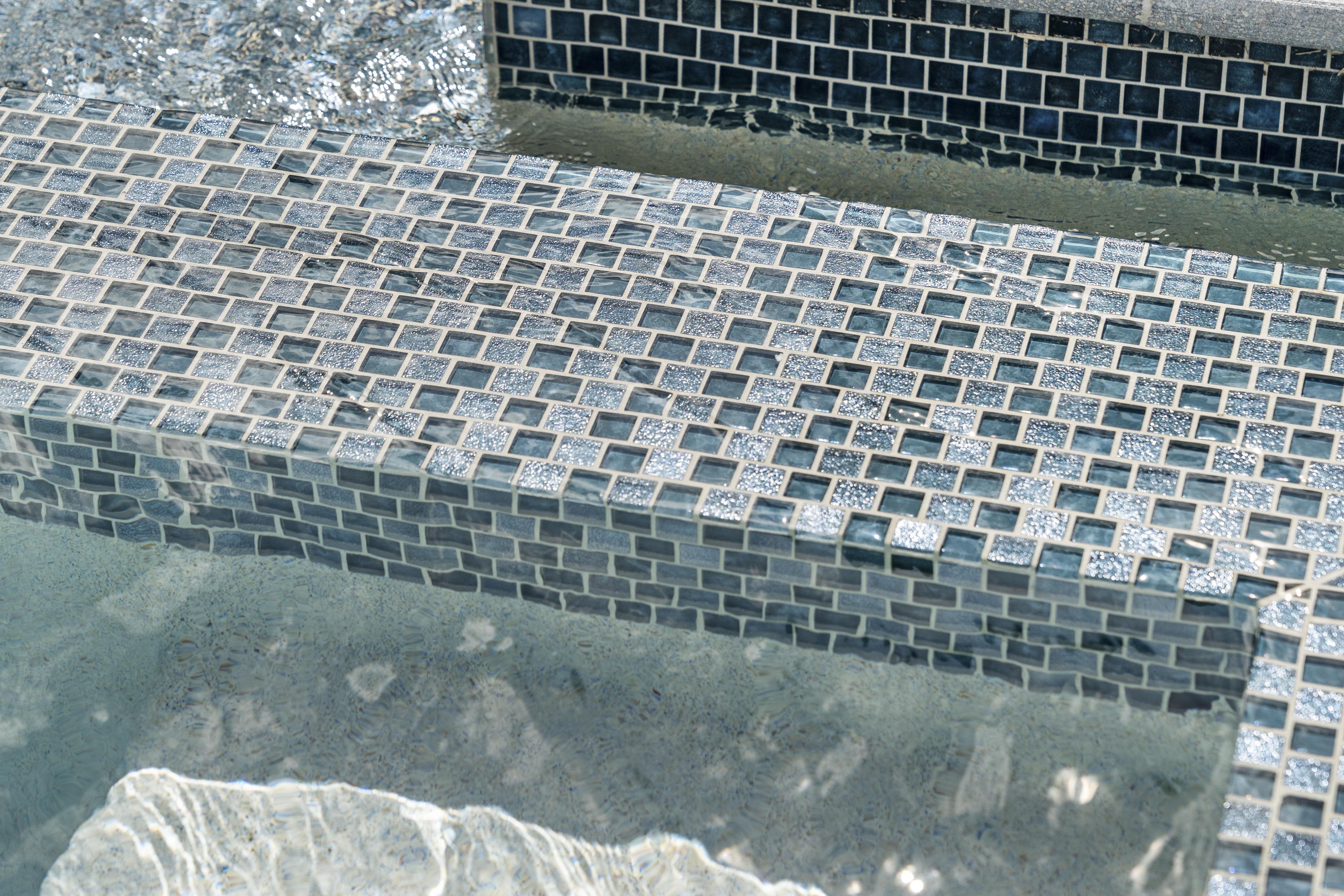 Full tile pool interior close-up, precision glass tile work with rich deep blue water