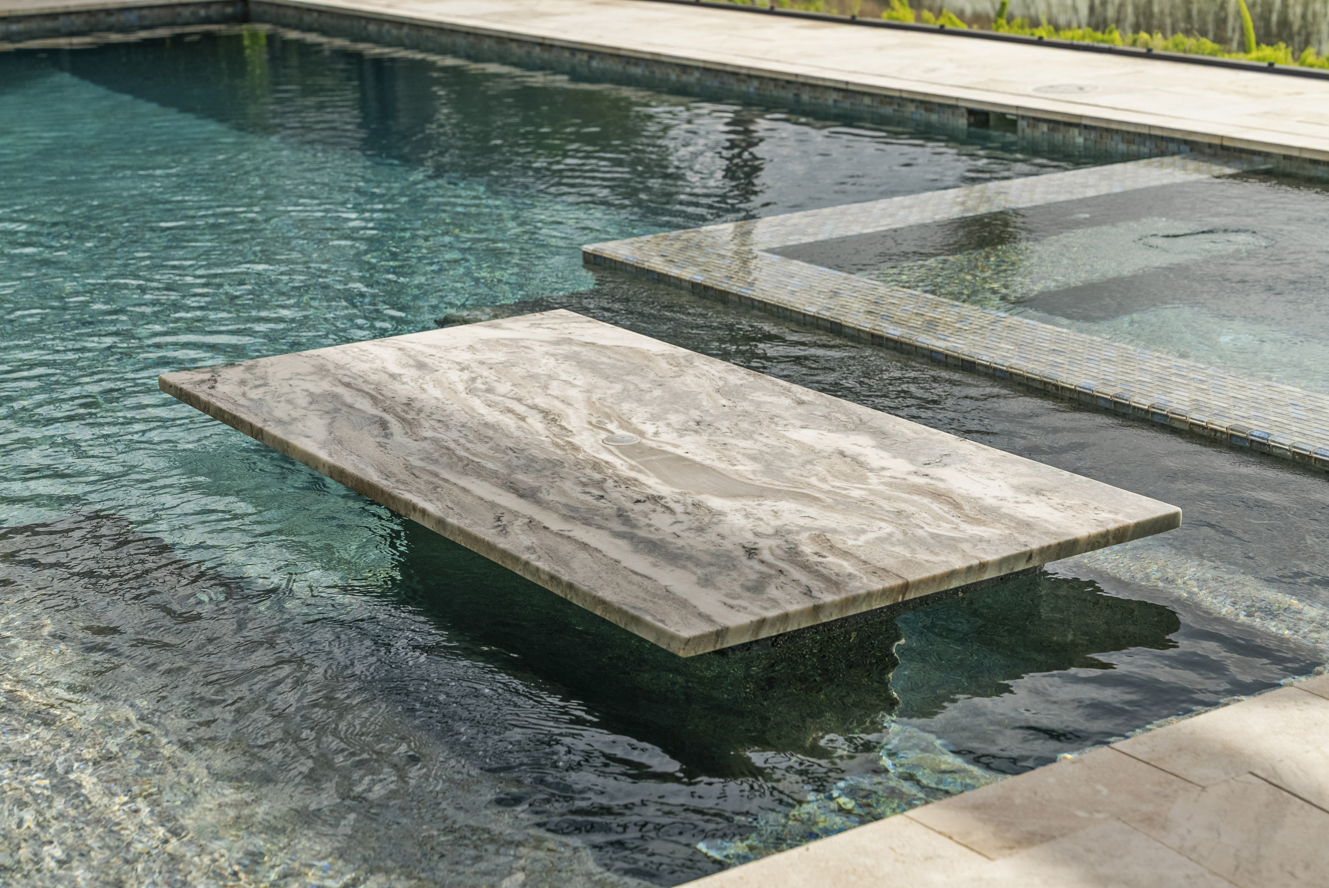 Spillover spa addition integrated with existing pool, evening shot with warm LED lighting